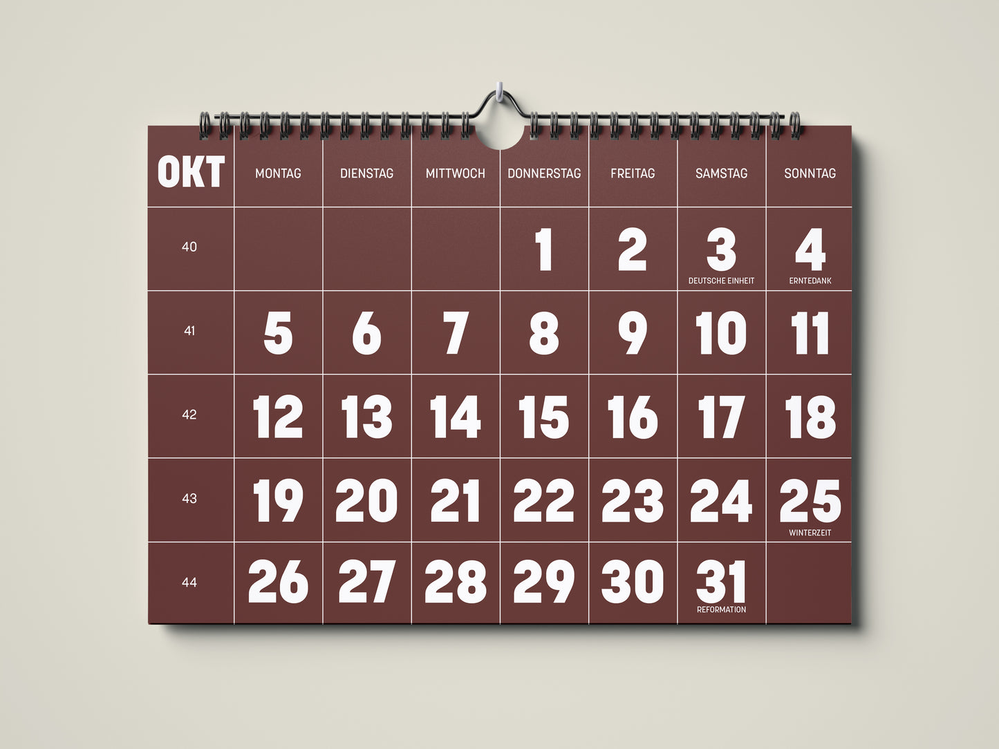 Kalender 2026: Bild eines Wandkalenders in Querformat DIN A4. Der Kalender ist minimalistisch. Jedes Kalenderblatt hat eine monatstypische Farbgebung auf weißer Schrift. Hier ist das Kalenderblatt von Oktober zu sehen in der Farbe kastanienbraun.