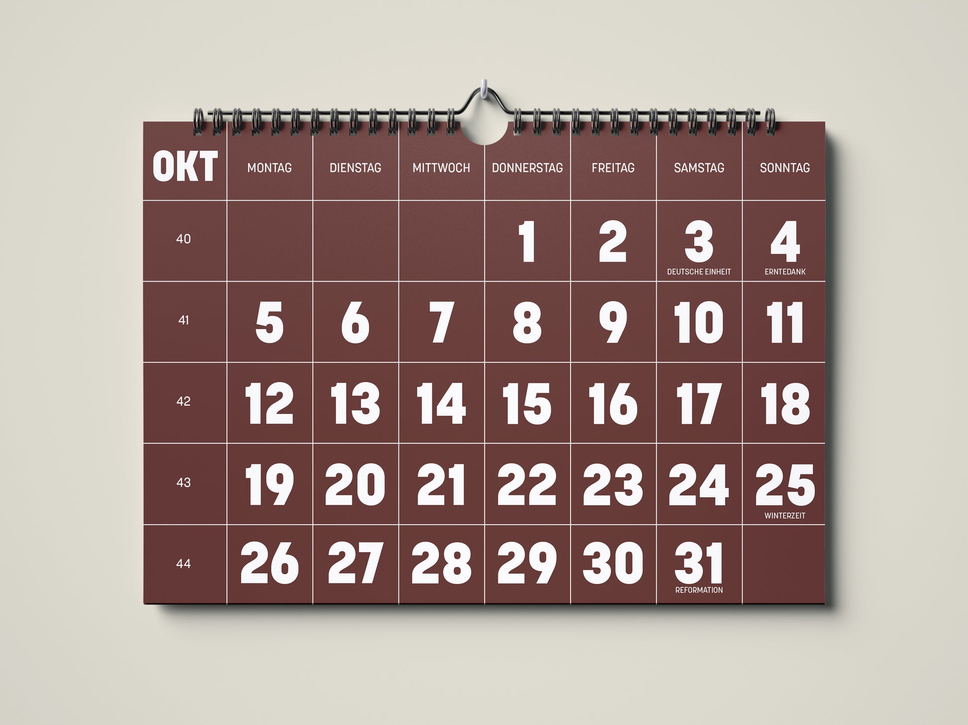 Kalender 2026: Bild eines Wandkalenders in Querformat DIN A4. Der Kalender ist minimalistisch. Jedes Kalenderblatt hat eine monatstypische Farbgebung auf weißer Schrift. Hier ist das Kalenderblatt von Oktober zu sehen in der Farbe kastanienbraun.